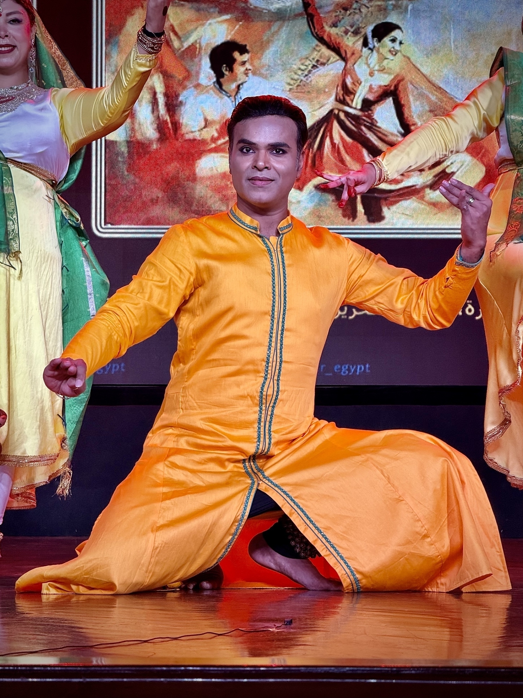 A person in vibrant traditional attire is performing a dance on stage.